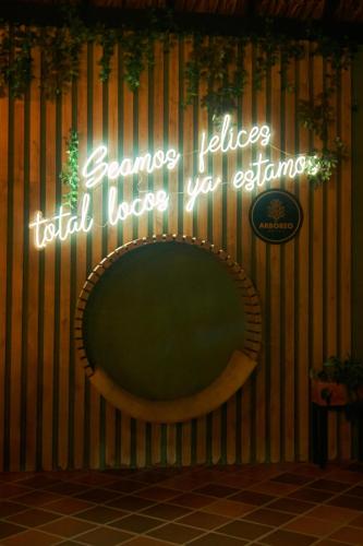 a neon sign on a wall with a round mirror at Hotel Arbóreo Doradal in Doradal