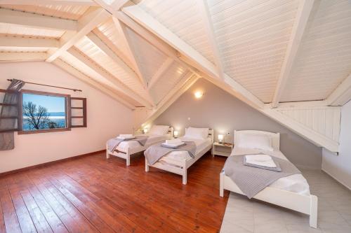 a attic room with three beds and a window at Southbank seafront apartments in Katelios
