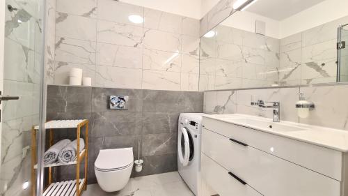 a bathroom with a toilet and a sink and a washing machine at Spa Residence Carbona 101, 307 Apartman in Hévíz