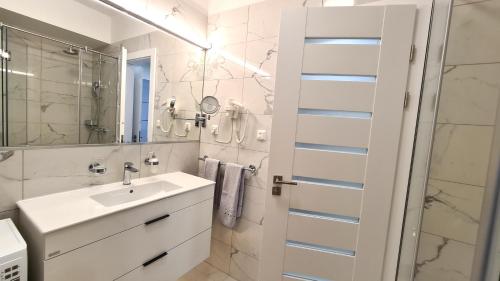 a white bathroom with a sink and a mirror at Spa Residence Carbona 101, 307 Apartman in Hévíz