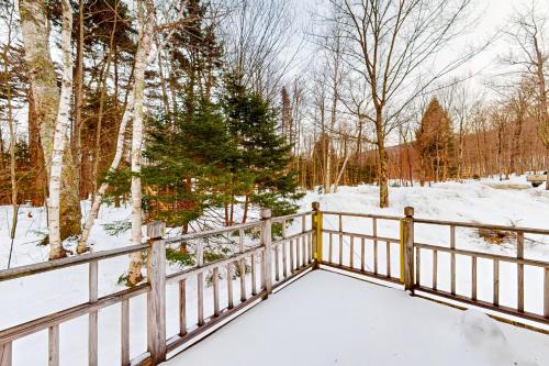 a wooden fence in the snow with trees at Mt Ellen Ski Chalet in Waitsfield