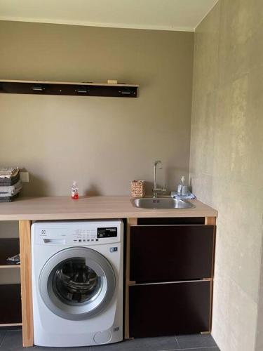 a kitchen with a washing machine and a sink at A Cozy Retreat - Sauna & Garden - 3BDR in Pärnamäe