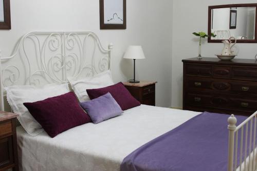 een slaapkamer met een wit bed met paarse en witte kussens bij 2 bedrooms house with private pool terrace and wifi at Paredes de Coura in Paredes de Coura