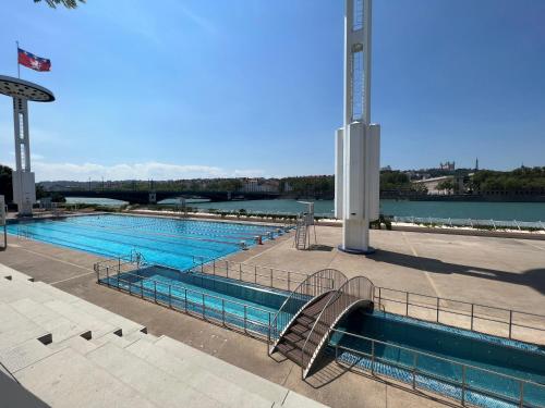 une grande piscine à côté d'un corps d'eau dans l'établissement Lyon Premium - Aux Berges du Rhône, à Lyon