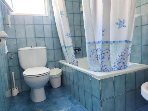 uma casa de banho em azulejos azuis com um WC e uma cortina de chuveiro em 4 bedrooms house at Punta Umbria 100 m away from the beach with terrace and wifi em Punta Umbría