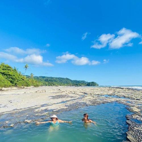 two people swimming in the water on a beach at Luz de Estrella Studios in Cabuya