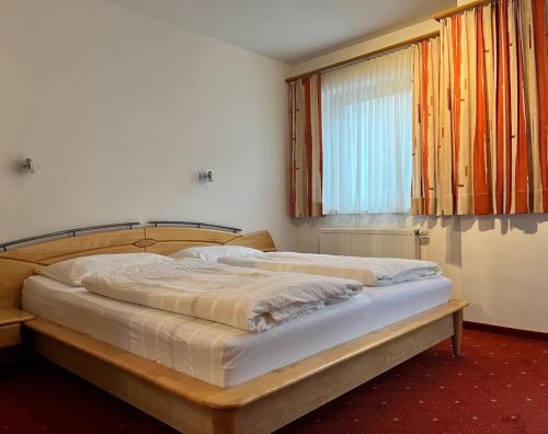 a bedroom with a bed with a wooden frame and a window at Appartements Sonnwend in Gerlos
