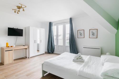 a white bedroom with a bed and a tv at Studio 20m2 Lumineux avec balcon - 2P in La Courneuve