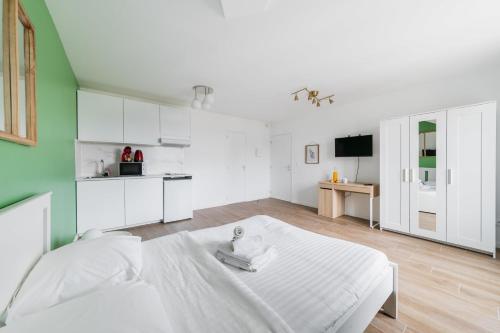 a white room with a bed and a kitchen at Studio 20m2 Lumineux avec balcon - 2P in La Courneuve