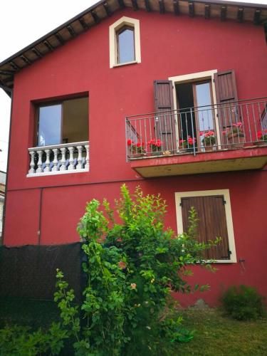 a red building with balconies and flowers on it at One bedroom appartement with jacuzzi and wifi at Sant'Ippolito in SantʼIppolito