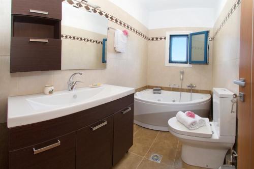 a bathroom with a sink and a toilet and a tub at Regina Ioanna Villas in Ayia Evfimia