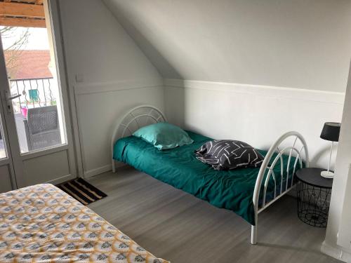 ein kleines Zimmer mit einem Bett mit einer grünen Decke in der Unterkunft Chambre triple spacieuse pour 3 Adultes avec terrasse privée - Proche Disneyland Paris in Mareuil-lès-Meaux