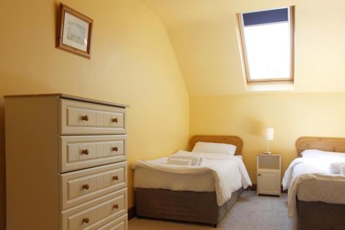 利特里姆的住宿－Leitrim Quay - Riverside Cottage 6，一间卧室设有两张床、一个梳妆台和窗户。