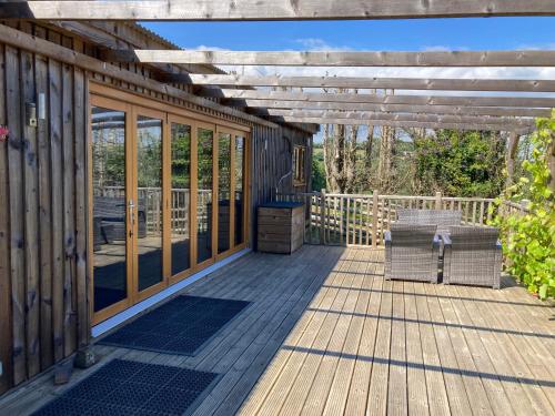 a deck with a pergola and a table and chairs at Unique Private Lodge in Cornwall sleeps 4 