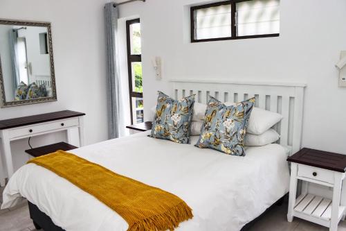 una camera da letto con letto bianco, cuscini e specchio di No1 Wenonah Trafalgar a Southbroom