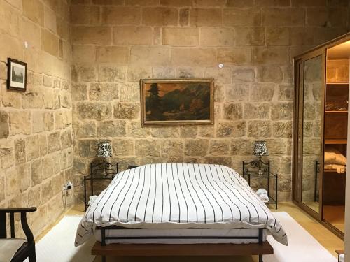 a bed in a room with a stone wall at Charming 17th Cent House of Character in the famous 3 Cities, right next to Valletta in Cospicua