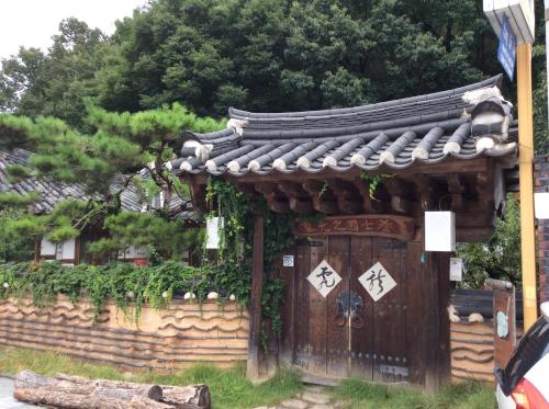 an oriental building with a gate in a garden at Yangsajae in Jeonju