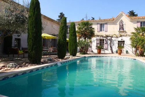 a swimming pool in front of a house with trees at Propriete d'une chambre avec piscine partagee et wifi a Saint Gilles in Saint-Gilles