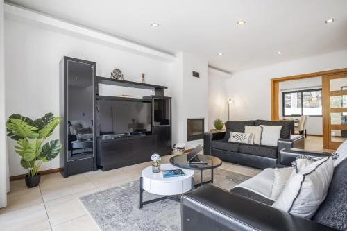 ein Wohnzimmer mit einem Sofa und einem großen TV in der Unterkunft Til Home by Madeira Sun Travel in Funchal