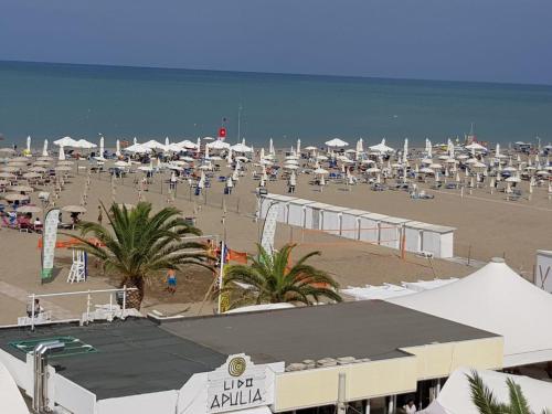 uma praia com muitos guarda-sóis e cadeiras em La Vela Apulia Seaside Residence em Margherita di Savoia