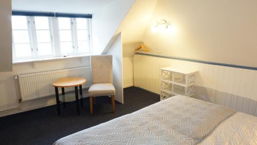 um quarto com uma cama, uma cadeira e uma janela em Marthas Insel em Oldenswort