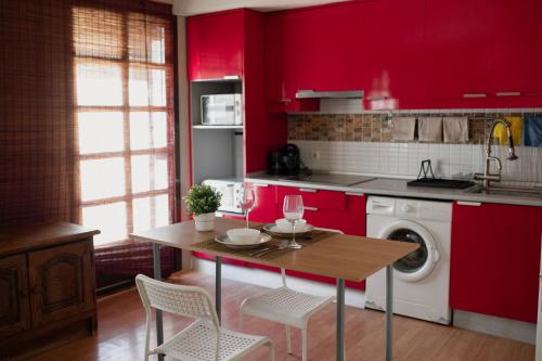 a kitchen with red cabinets and a table with chairs at Apartamento El Catavino in Jerez de la Frontera