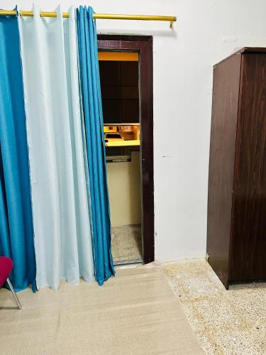 una puerta abierta con cortinas azules en una habitación en Room for rent, en Sharjah
