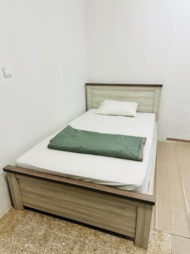 1 cama con sábanas blancas y marco de madera en Room for rent, en Sharjah