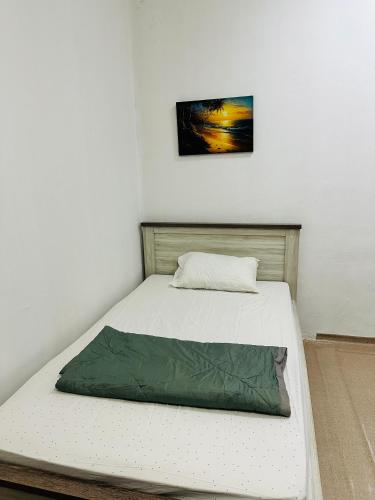 Una cama con una manta verde en una habitación en Room for rent, en Sharjah