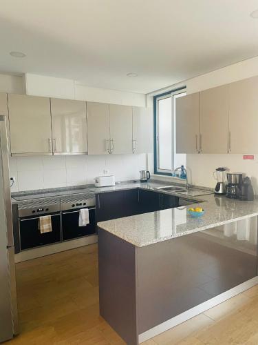 a kitchen with white cabinets and a granite counter top at Inncork Guesthouse in Ponte de Sor