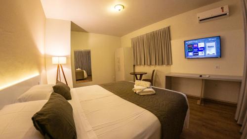 een hotelkamer met 2 bedden en een flatscreen-tv bij Dom Ravello in Telêmaco Borba