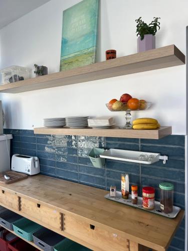 a kitchen with wooden shelves with plates and fruit at YEY Baleal in Peniche