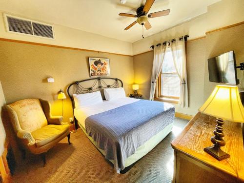 a bedroom with a bed and a chair and a fan at Hotel Vendome in Prescott