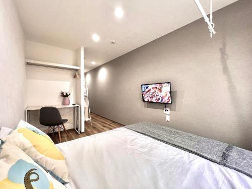 a bedroom with a bed and a tv on the wall at ANX Hostel in Tokyo