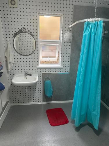 bagno con tenda doccia blu e lavandino di Best east London location a Londra