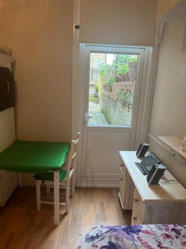 Habitación con escritorio, silla verde y ventana. en Best east London location en Londres