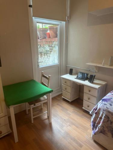 a bedroom with a green table and a bed and a window at Best east London location in London