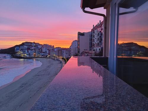 a view of the beach and buildings at sunset at Apartamento Sisargas in Malpica