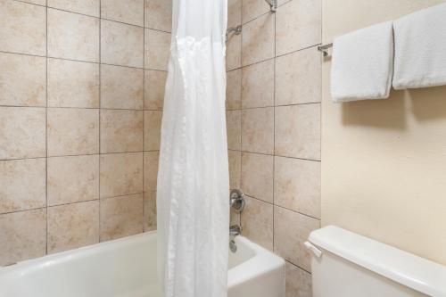 a bathroom with a white shower curtain and a tub at Suburban Studios International Drive in Orlando