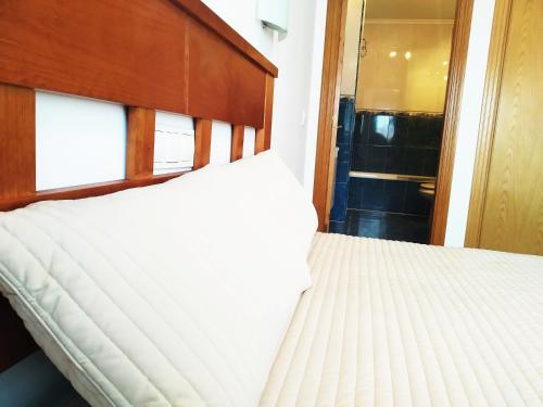 a bedroom with a bed with a wooden headboard at HIKARI, centro Luanco con PARKING in Luanco