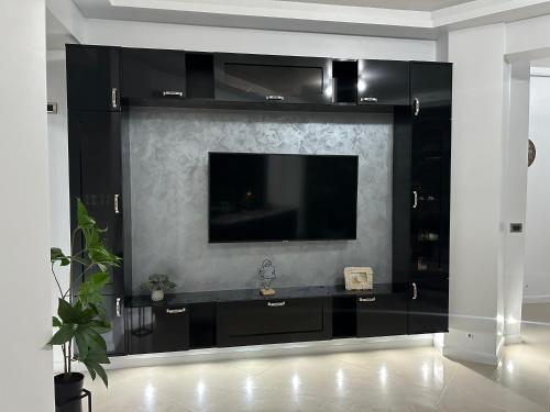 een zwart entertainmentcentrum met een tv aan de muur bij New Eva Unique Luxury Apartament in Mamaia Nord – Năvodari