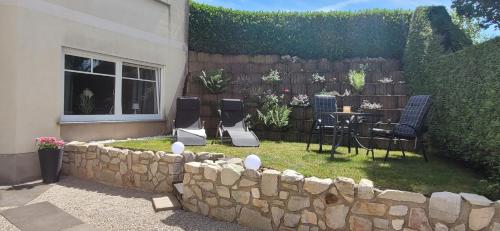 a backyard with a stone wall and a table and chairs at Ferienwohnung MIA in Flußbach