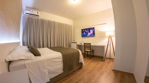 a hotel room with a bed and a table and a desk at Dom Ravello in Telêmaco Borba