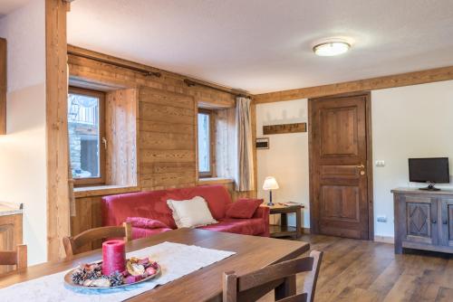 een woonkamer met een rode bank en een tafel bij Maison Lo Triolet in Introd