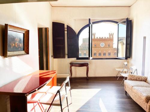 een woonkamer met een tafel en een groot raam bij Il Campo 8: Piazza del Campo in Siena