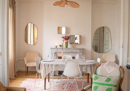 uma sala de jantar com mesa, cadeiras e espelhos em Rare! Magnifique appartement - Vue Cathédrale em Reims
