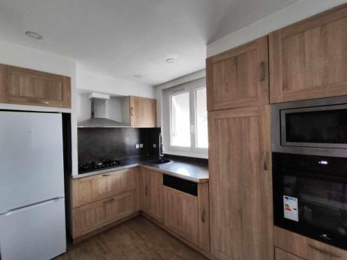 une cuisine avec des armoires en bois et un réfrigérateur blanc dans l'établissement Appartement Avignon 3 Chambres, à Avignon