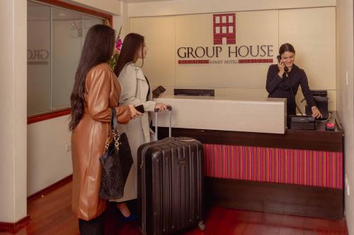 Group House Apart Hotel في كوسكو: امرأتان واقفتان على منضدة مع امرأة تتحدث على الهاتف الخلوي