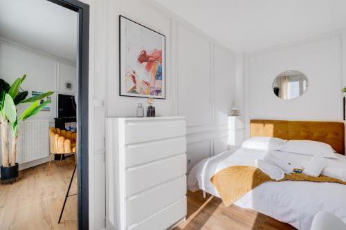 une chambre blanche avec un lit et un miroir dans l'établissement Le Panoramique - clim, balcon, superbe vue, wifi, à Toulouse