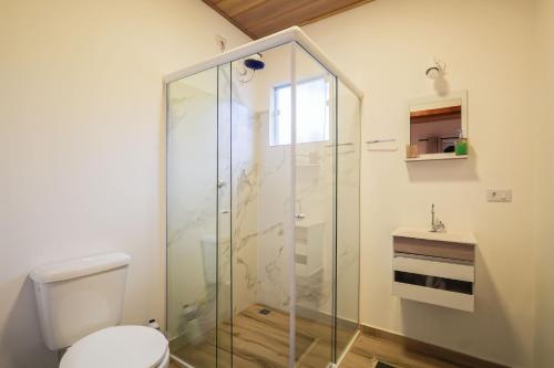 a bathroom with a glass shower stall and a toilet at Terra Sertaneja - Chalé Evidências II in Piedade